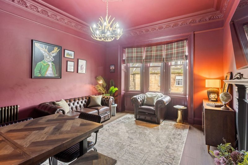 Pink living room with chandelier, fireplace, desk, armchairs and framed wall art