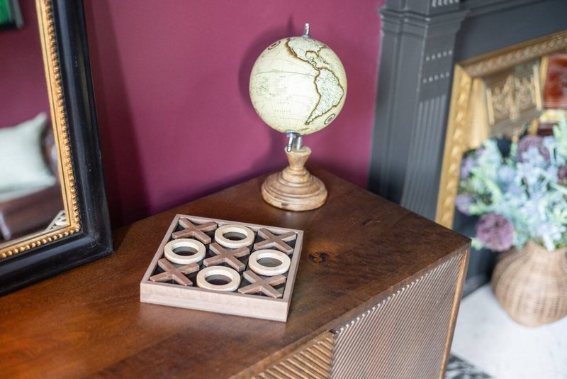Wooden dresser with decorative globe, framed mirror, and tabletop accessories against purple wall