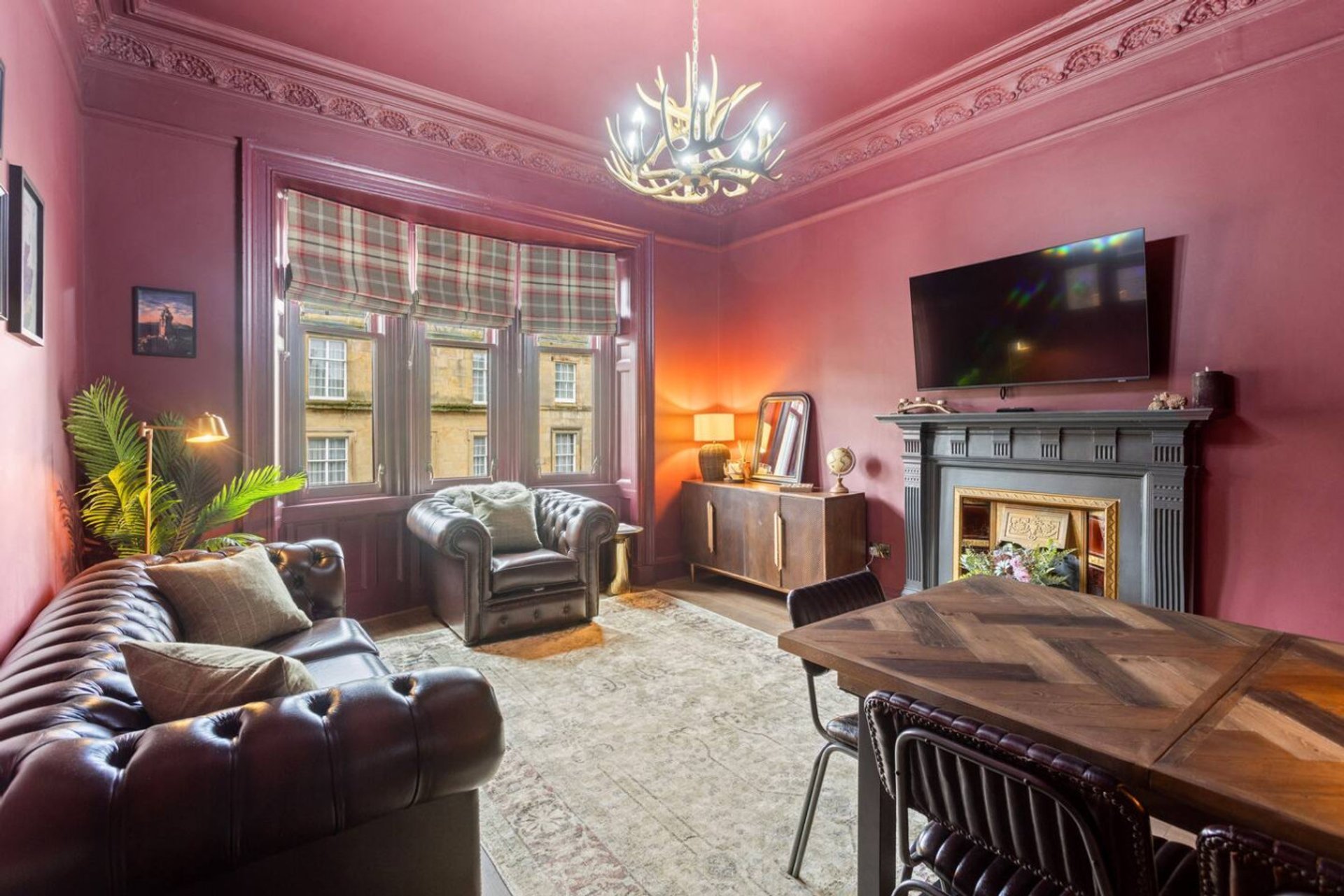 Pink living room with leather sofa, fireplace, chandelier, dining table and bay windows