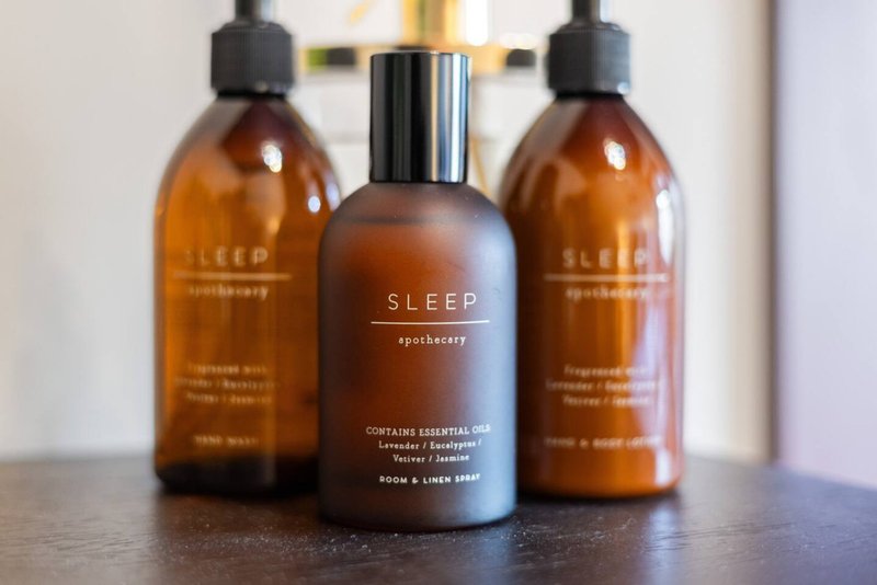 Three amber glass bottles of sleep apothecary product on dark counter