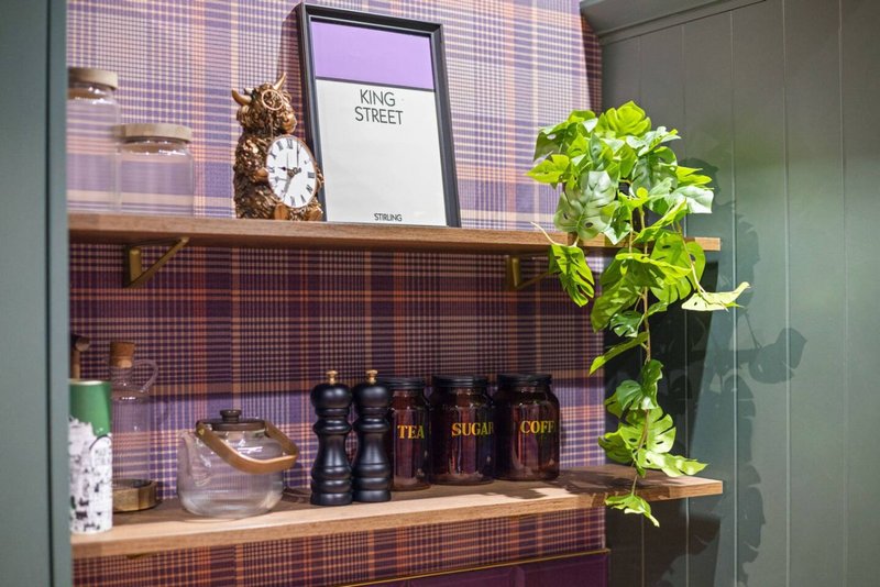 Wooden shelving unit with decorative items, books, plant, and toiletry bottles