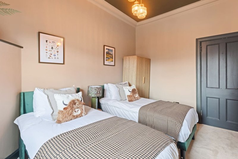 Twin bedroom with two beds, white bedding, teal headboards, and pendant light fixture