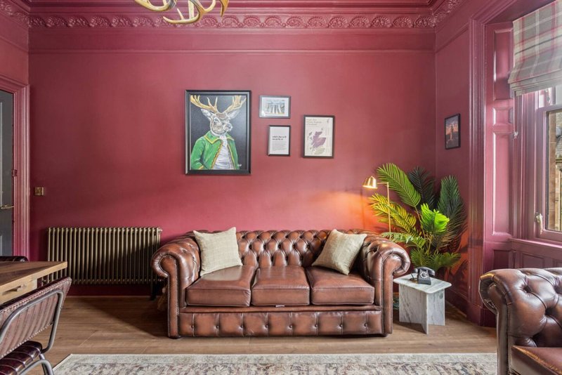 Pink living room with leather Chesterfield sofa, framed wall art, potted plant and radiator