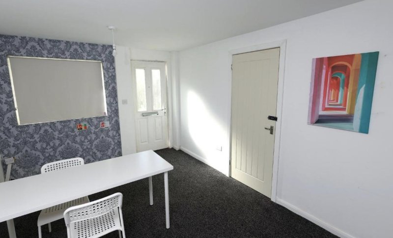 Separate office with white desk and chairs.
