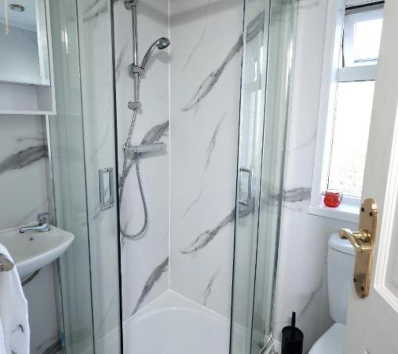 Modern bathroom with walk-in shower, sink, toilet and window