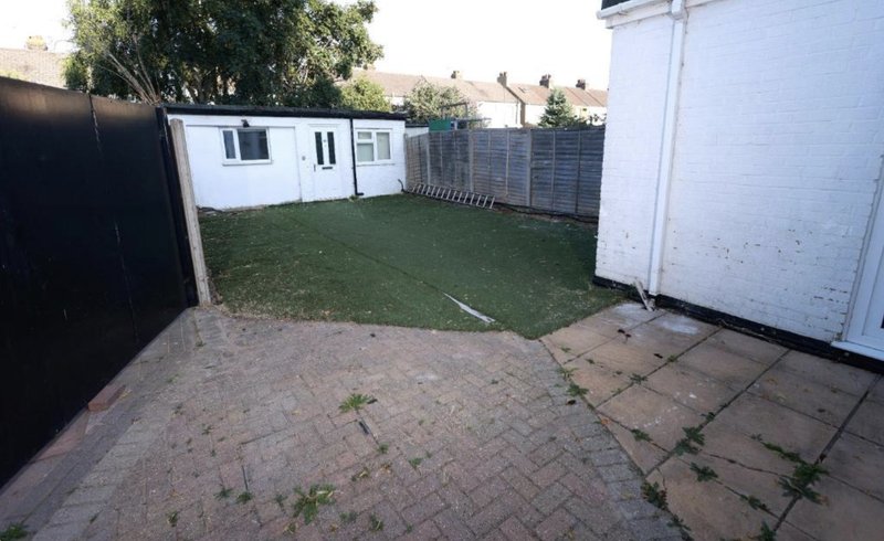 Backyard garden with paved patio, lawn area, fencing and outbuildings