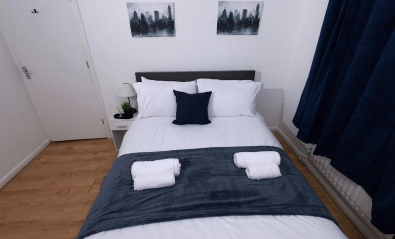 Bedroom with double bed, white bedding and wooden floor.