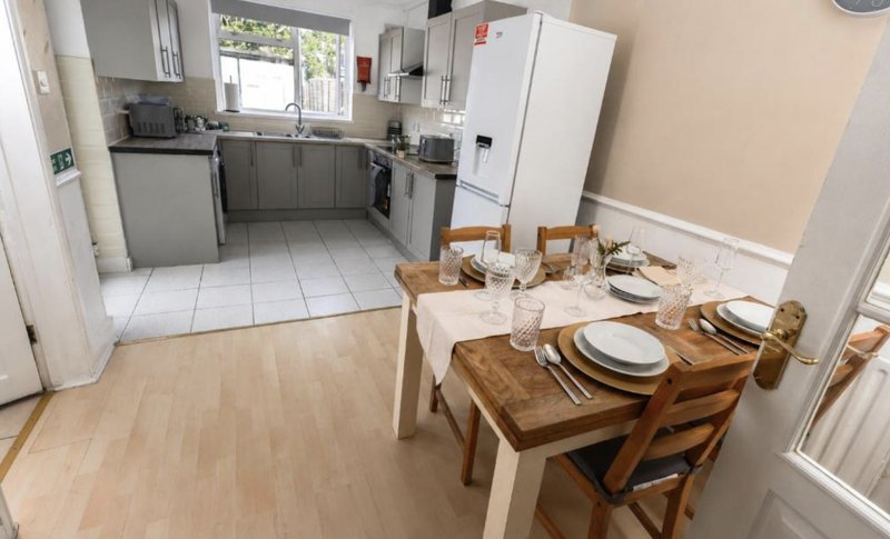 Open-plan kitchen and dining area with wooden table, place settings, and modern appliances