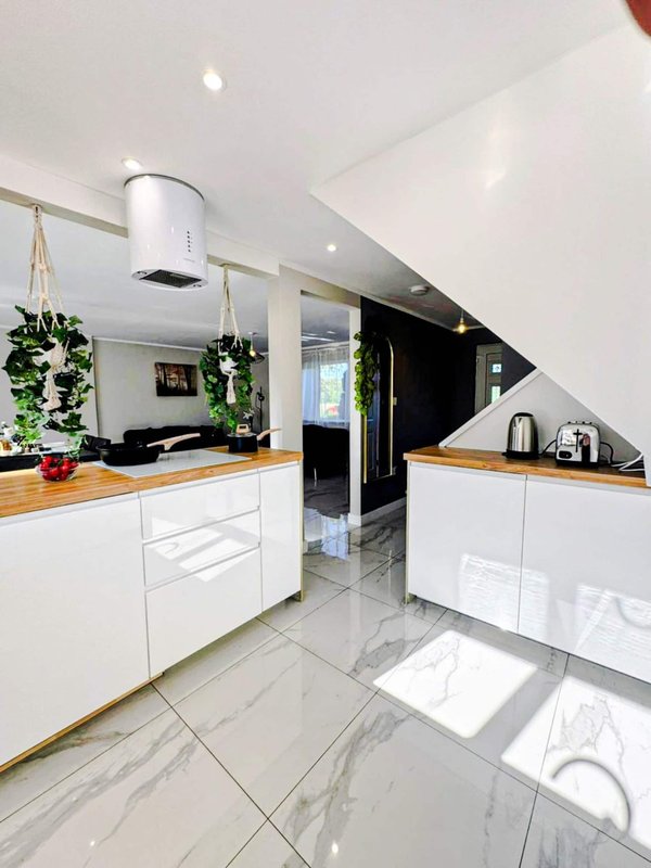 Modern kitchen with white cabinetry, wooden countertops, marble flooring and stairs