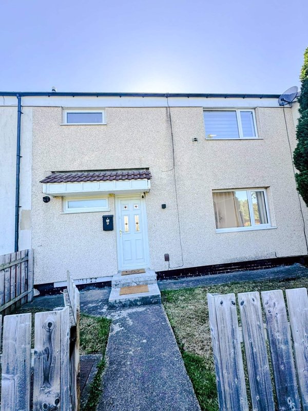 Modern two-storey house exterior with light render, blue door, multiple windows and driveway