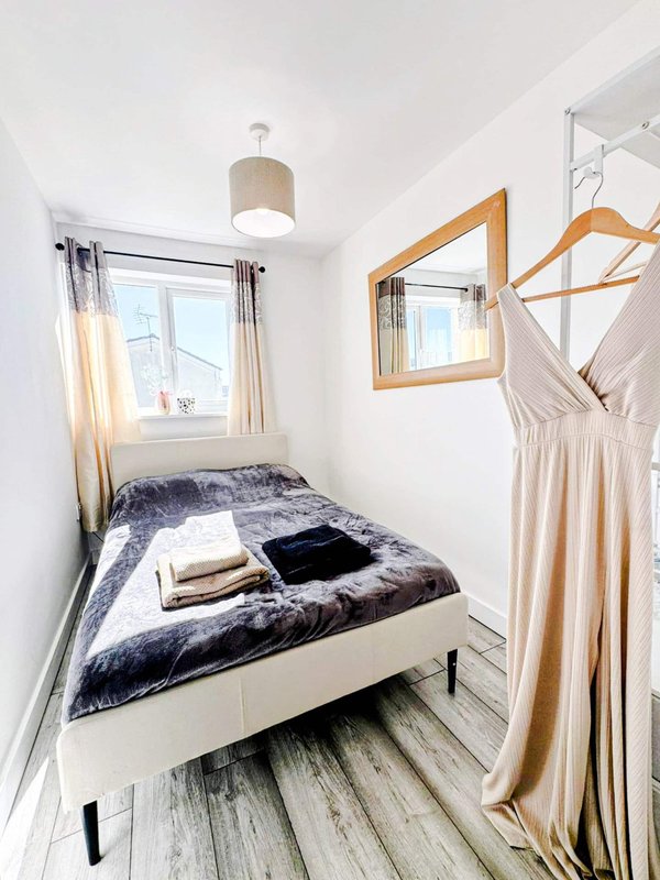 Compact bedroom with single bed, wooden wardrobe frame, pendant light and window