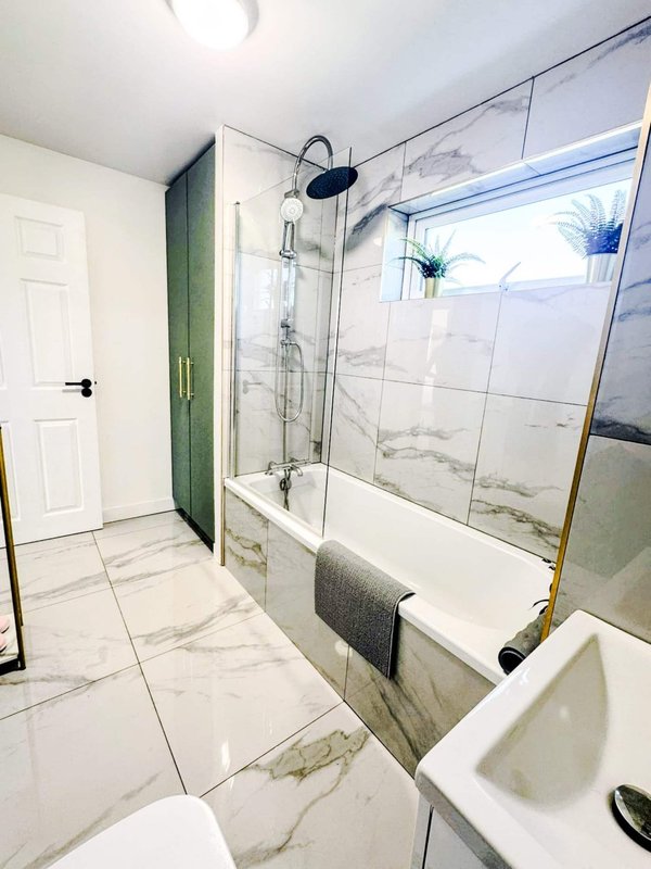 Modern bathroom with marble-effect tiles, glass shower enclosure and white vanity sink