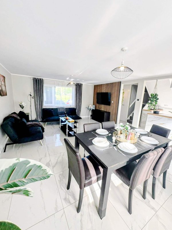 Open-plan living and dining area with dining table, chairs, sofa, and modern furnishings