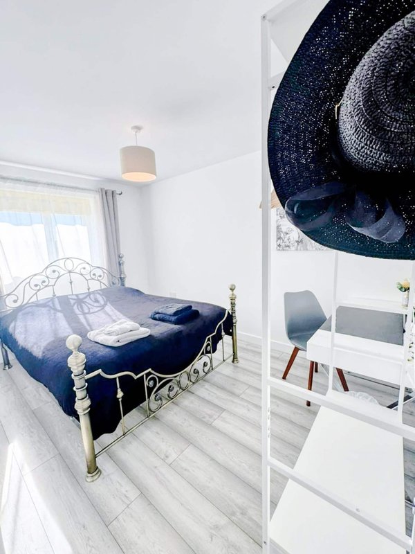 Bright bedroom with metal bed frame, navy bedding, wooden floor and pendant light