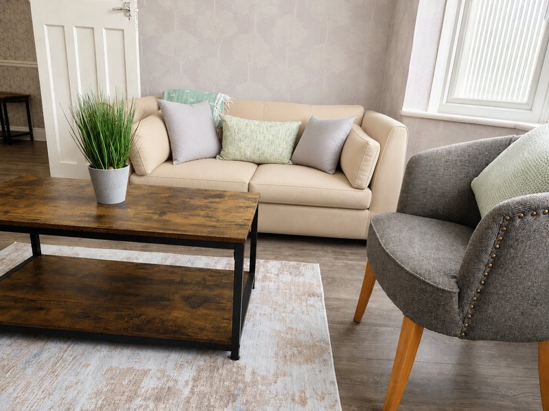 Living room with beige sofa, gray armchair, wooden coffee table and potted plant