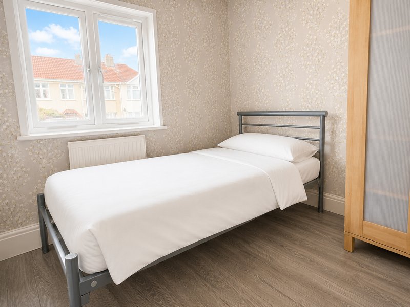 Bright bedroom with single bed, metal frame, wooden floor and window view