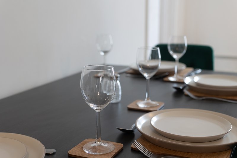 Dining table set with wine glasses, plates, cutlery and place settings