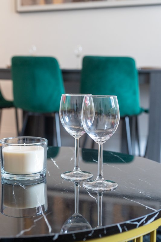 Dining table with wine glasses, candle, and teal upholstered chairs in background