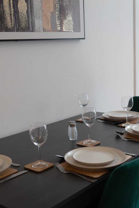 Dining table set with plates, glasses, cutlery and abstract wall art above