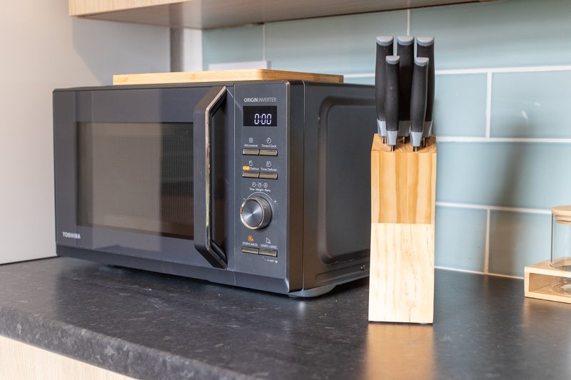 Kitchen counter with microwave oven, knife block, and minimalist cabinetry