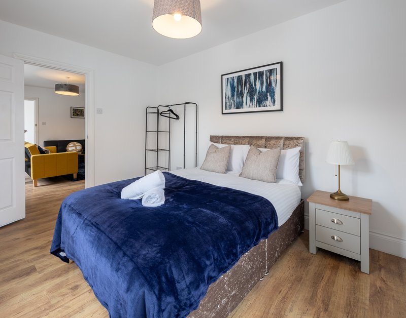 Bedroom with double bed, blue velvet throw, wooden flooring, and pendant ceiling light