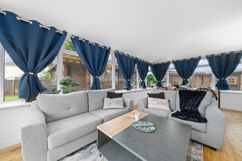 Spacious living room with gray sectional sofa, dark coffee table, blue curtains and large windows