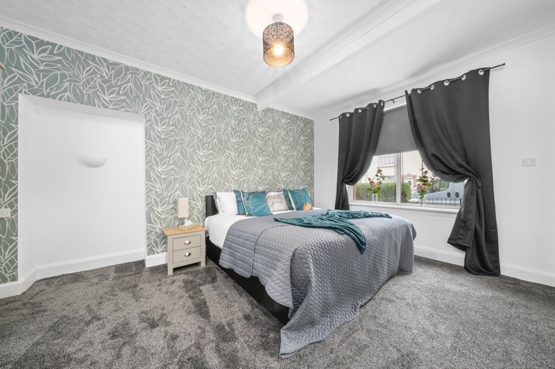 Modern bedroom with double bed, patterned wallpaper, dark curtains and ceiling lamp