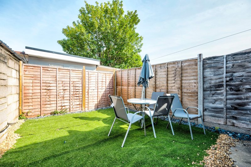 Garden patio area with table, chairs, lawn and wooden fencing