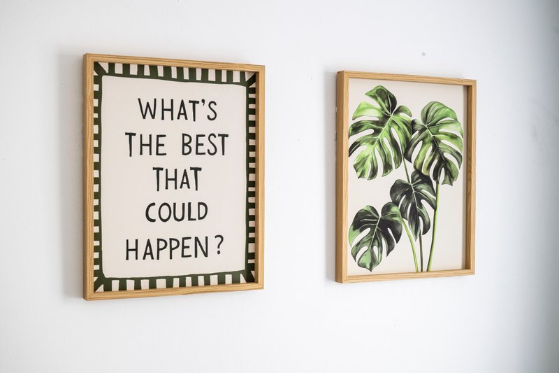 Two framed wall artworks: text print asking 'What's the best that could happen?' and botanical plant illustration