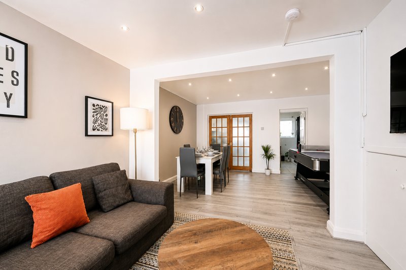 Open-plan living area with grey sofa, wooden table, and view into kitchen and dining space