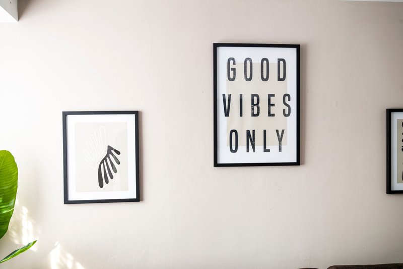 Modern bedroom wall with framed botanical and motivational prints above plant