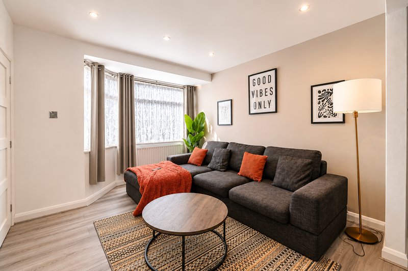 Modern living room with dark sofa, orange cushions, round table and large window