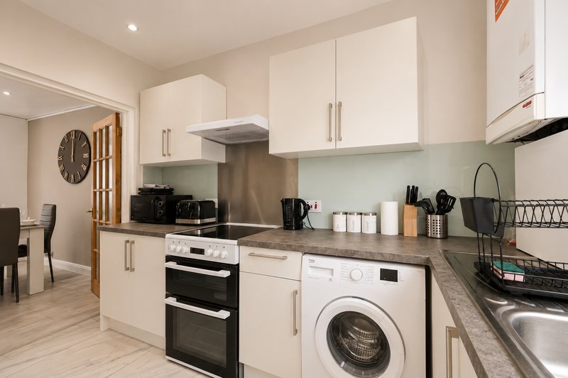 Modern kitchen with cream cabinetry, stainless steel appliances, washing machine and breakfast bar