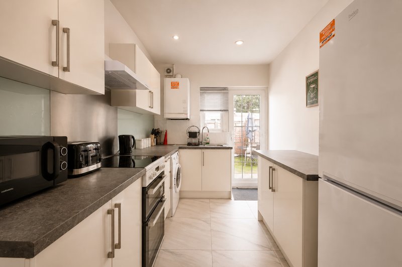Modern kitchen with cream cabinets, dark countertop, stainless steel appliances and garden view
