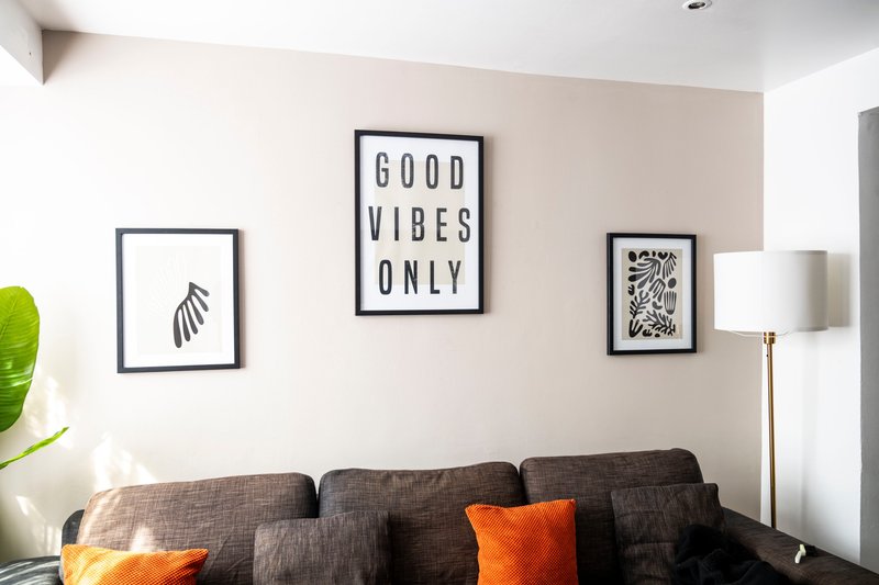 Living room with dark gray sofa, orange cushions, framed wall art and floor lamp