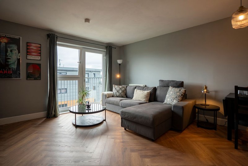 Modern living room with grey sofa, coffee table, balcony doors and waterfront view
