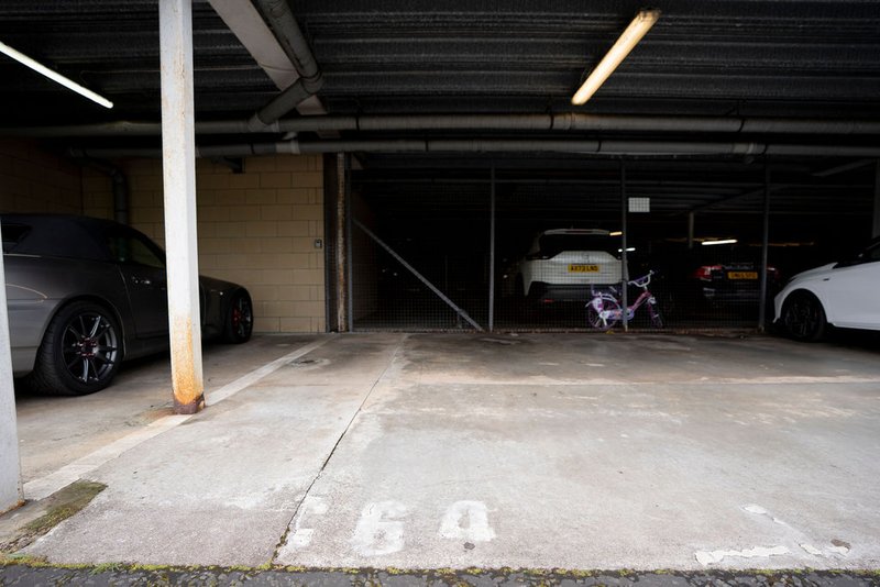 Covered parking garage with concrete floor, support columns, and parked vehicles