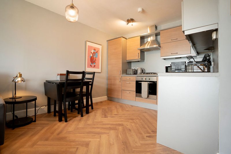Open-plan kitchen and dining area with wooden herringbone floor, modern cabinetry, and dining table