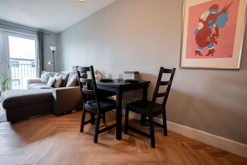 Open-plan living and dining area with sofa, dining table, chairs, and framed wall art