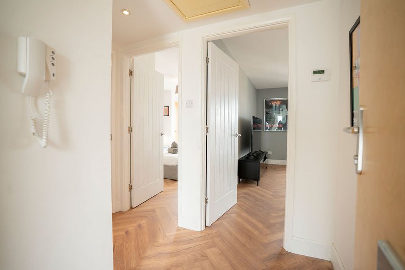 Bright hallway with wooden flooring, white doors, and access to multiple rooms