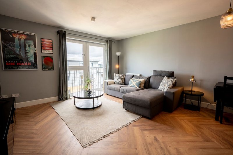 Modern living room with gray sofa, wooden floors, balcony doors and contemporary furnishings