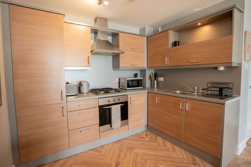 Modern kitchen with wooden cabinets, integrated appliances, and herringbone wood flooring
