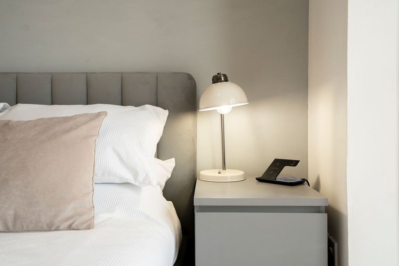 Modern bedroom with gray upholstered headboard, white bedding, and metal table lamp