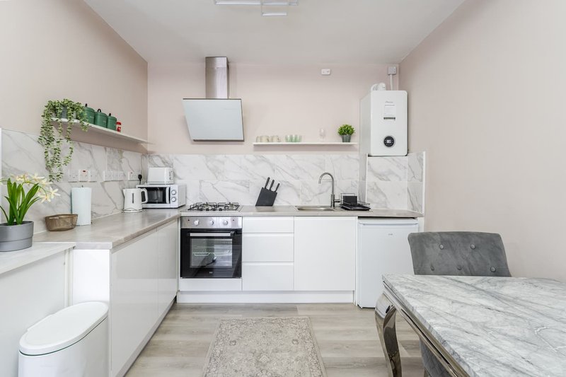 Modern white kitchen with marble backsplash, gas cooktop, white cabinetry and dining table