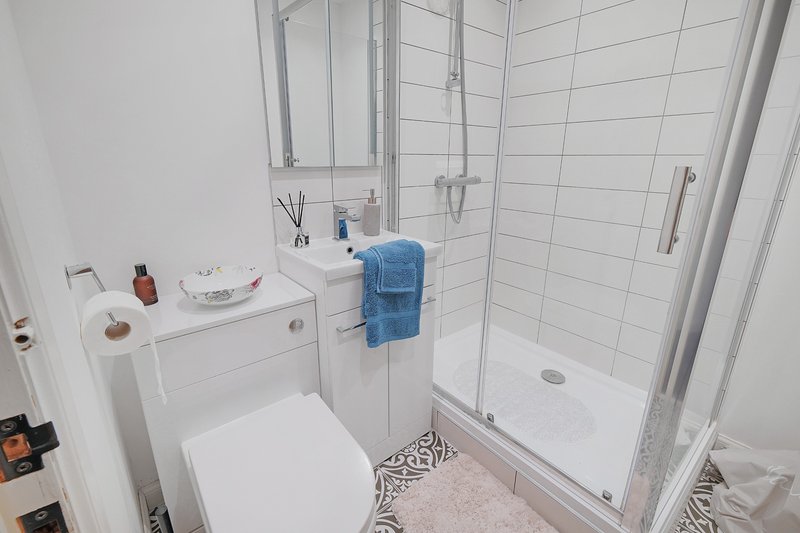 Clean modern bathroom with white toilet, sink, shower enclosure and blue towel