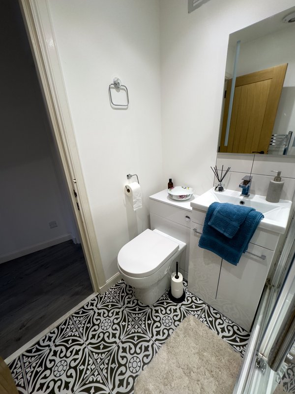 Modern bathroom with white toilet, vanity sink, mirror, and patterned floor tile
