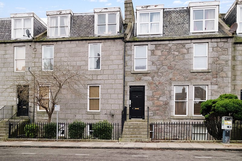Stone terraced townhouses with dormer windows, black doors, white-framed windows and front railings