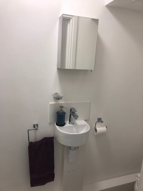 Bathroom wall-mounted sink with mirror cabinet, soap dispenser and towel rail
