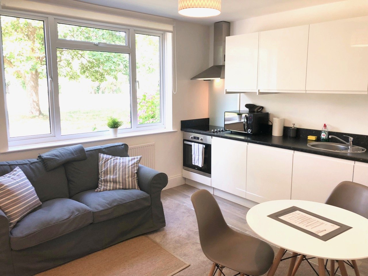 Open-plan kitchen and living area with sofa, dining table, and modern white cabinetry