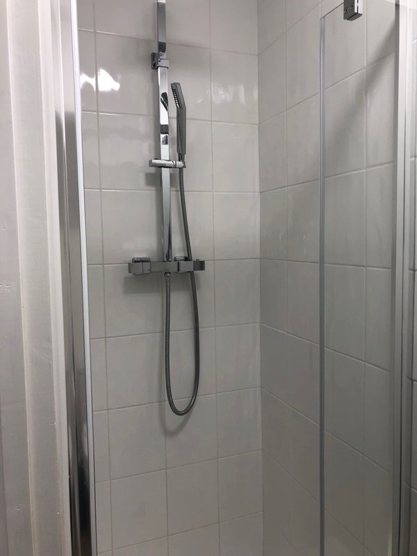Modern bathroom shower enclosure with glass door and chrome showerhead fixture